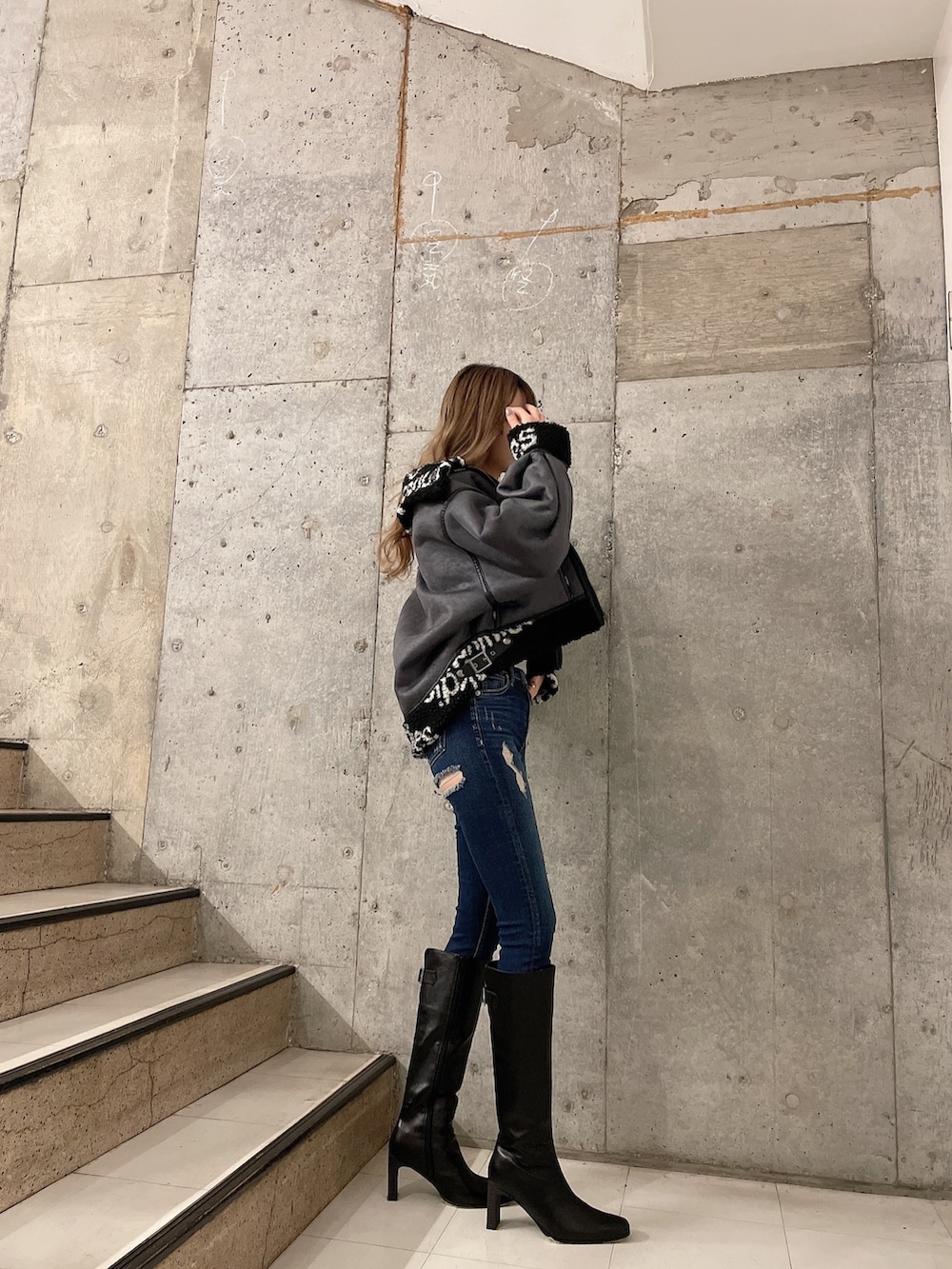 ブラック系のブルゾン、グレー系のスウェット、ブルー系のデニムパンツを着用したレディースの秋コーディネートの2枚目の写真