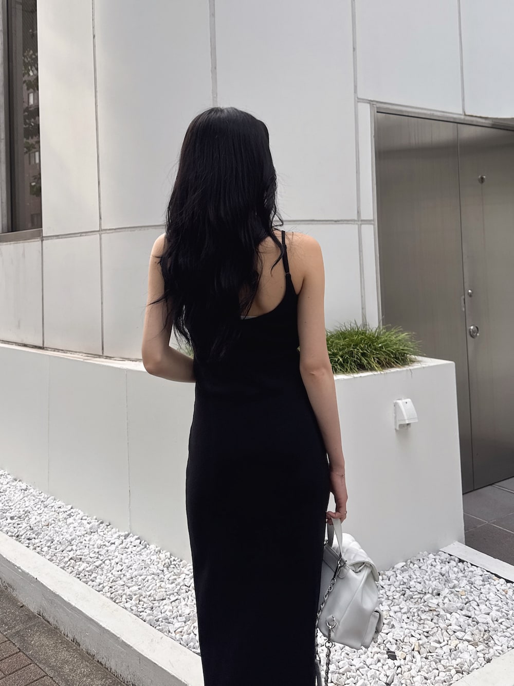 ブラック系のワンピース、ホワイト系のサンダル、ホワイト系のバックパック/リュックを着用したレディースの夏コーディネートの5枚目の写真