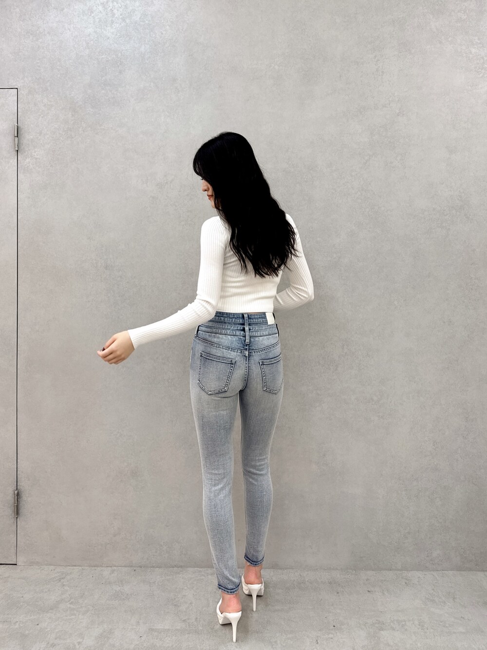 ホワイト系のニット/セーター、ブルー系のデニムパンツ、ホワイト系のパンプスを着用したレディースの冬コーディネートの3枚目の写真