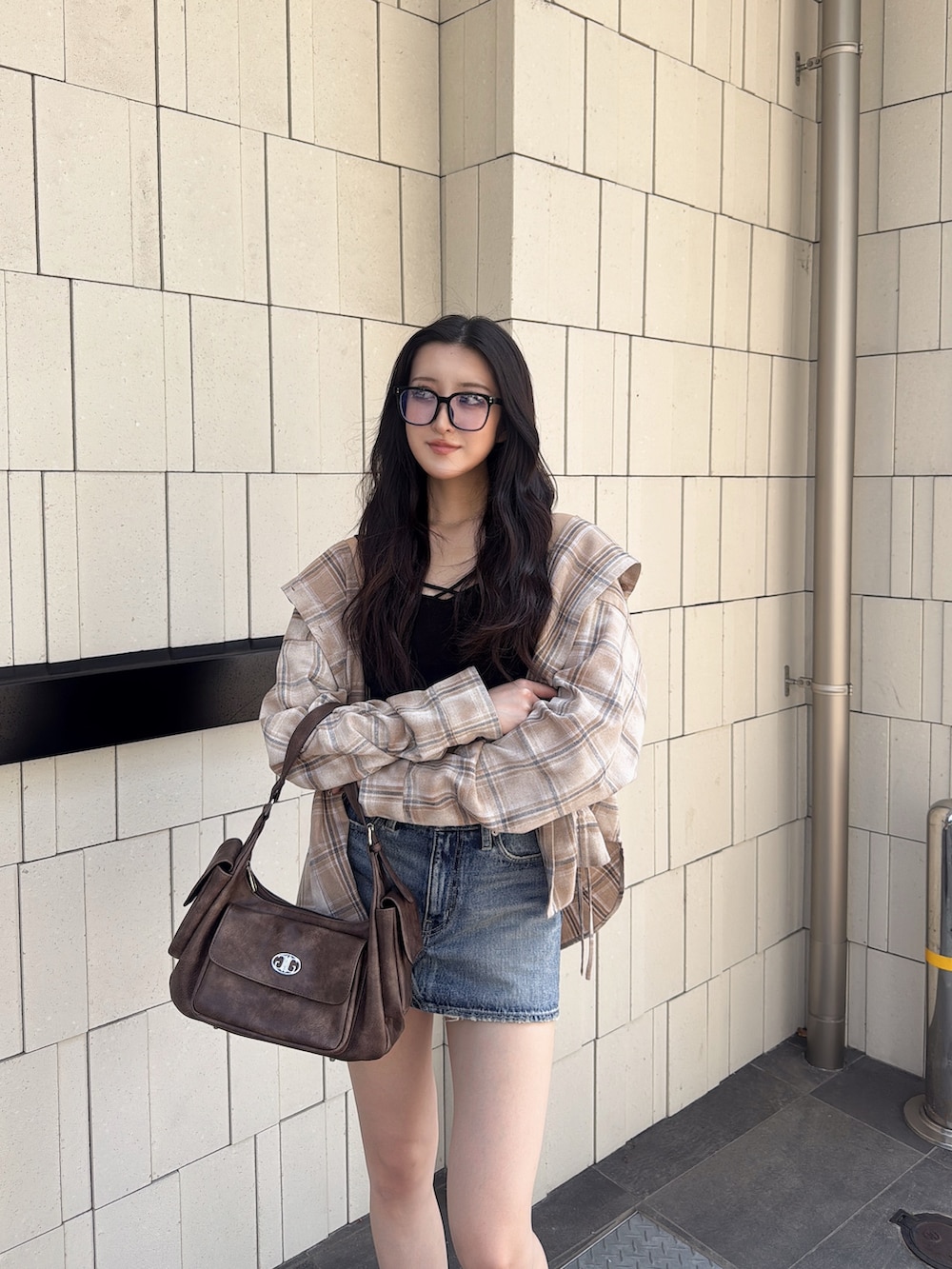 ブルー系のデニムスカート、ブラウン系のハンドバッグ、ベージュ系のシャツ/ブラウスを着用したレディースの夏コーディネートの3枚目の写真