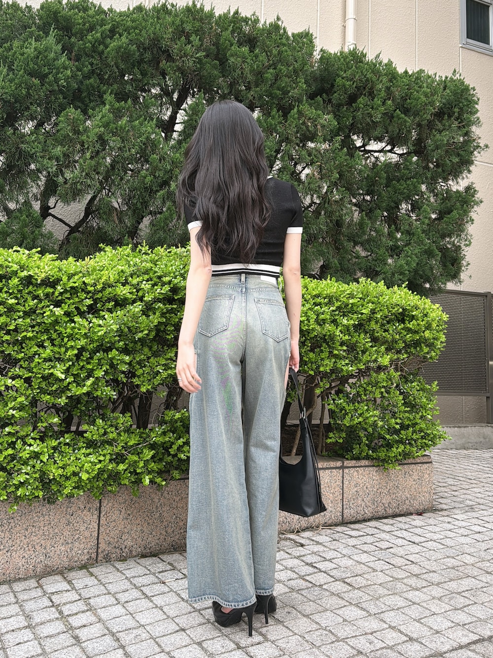 ブラック系のニット/セーター、ブルー系のデニムパンツ、ブラック系のパンプスを着用したレディースの春コーディネートの3枚目の写真