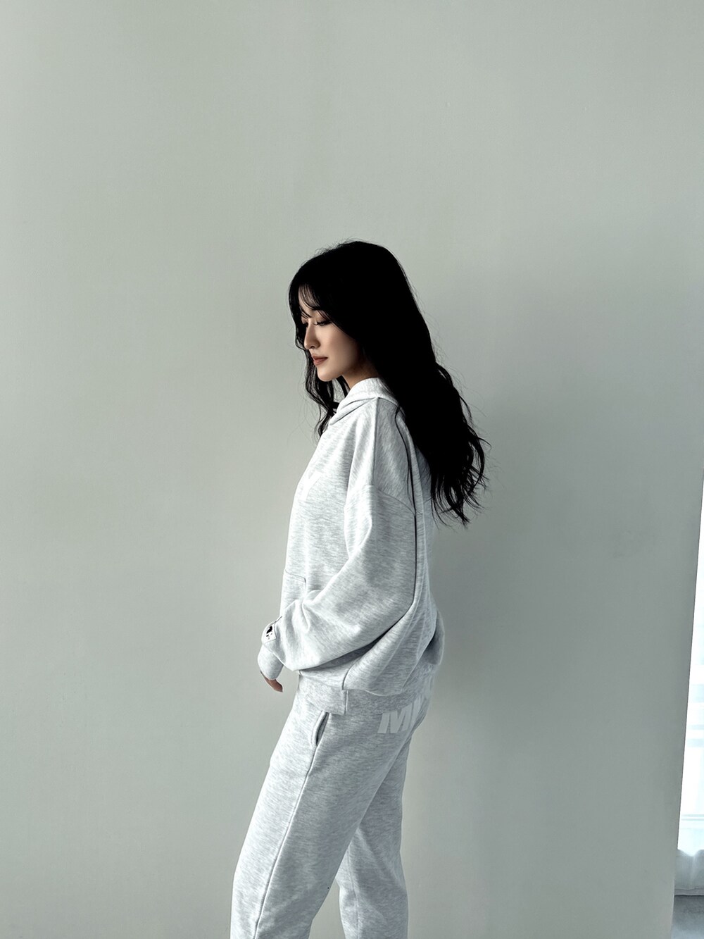 グレー系のパーカー、グレー系のスウェットパンツ、ホワイト系のパンプスを着用したレディースの秋コーディネートの4枚目の写真