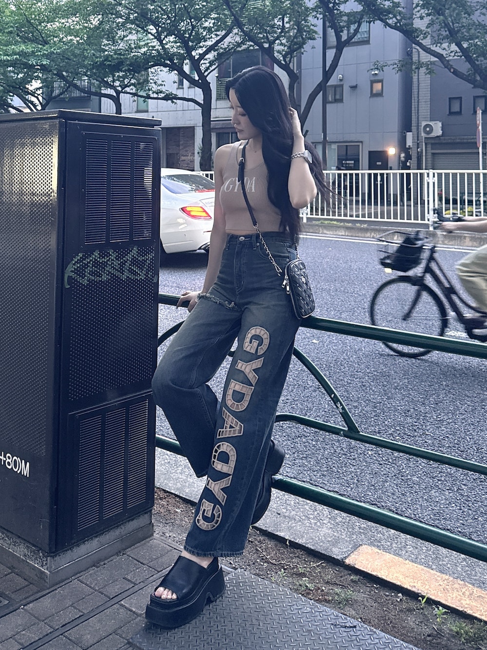 ベージュ系のキャミソール、ブルー系のデニムパンツ、ブラック系のショルダーバッグを着用したレディースの夏コーディネートの4枚目の写真