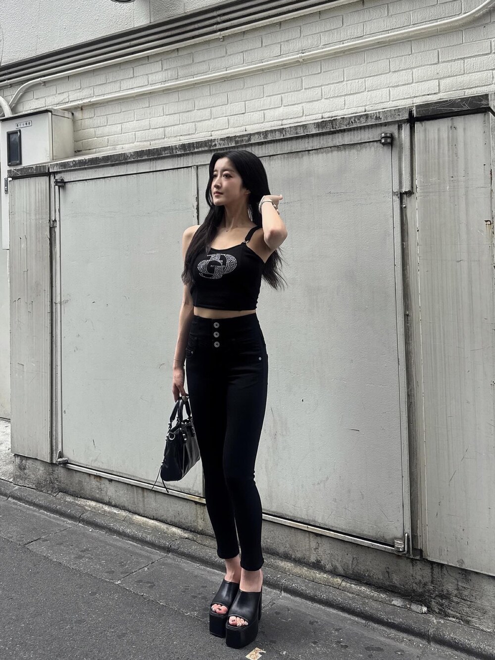 ブラック系のデニムパンツ、ブラック系のキャミソール、ブラック系のサンダルを着用したレディースの夏コーディネートの5枚目の写真