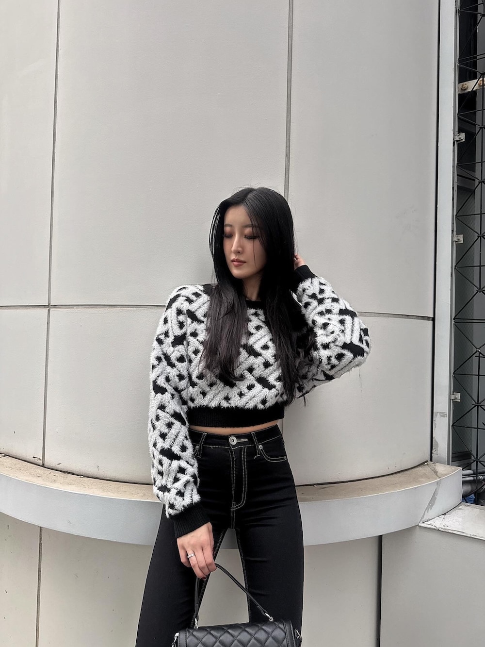 ブラック系のニット/セーター、ブラック系のデニムパンツ、ブラック系のブーツを着用したレディースの冬コーディネートの2枚目の写真