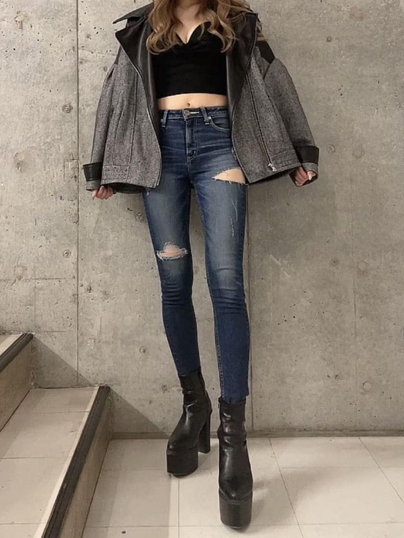 ブラック系のキャミソール、ブラック系のブーツ、ブルー系のデニムパンツを着用したレディースの秋コーディネートの2枚目の写真