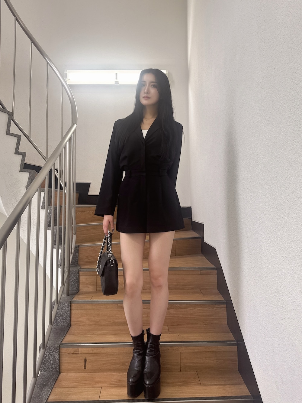 ブラック系のつなぎ/オールインワン、ブラック系のブーツ、ブラック系のハンドバッグを着用したレディースの秋コーディネートの3枚目の写真