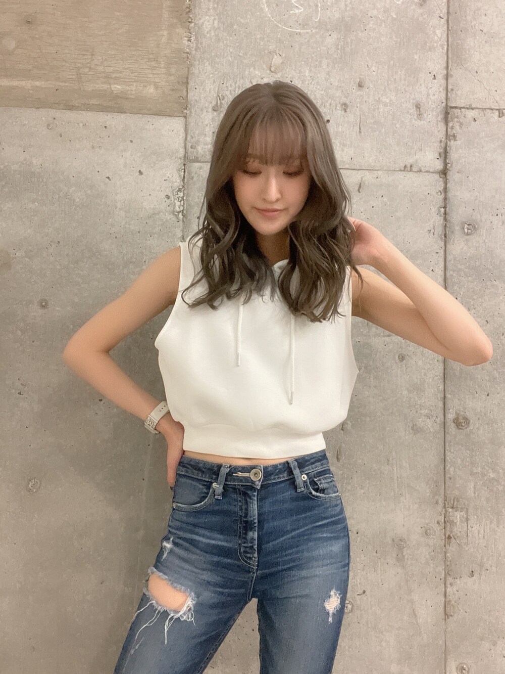 ホワイト系のパーカー、ブラック系のサンダル、ブルー系のデニムパンツを着用したレディースの夏コーディネートの3枚目の写真