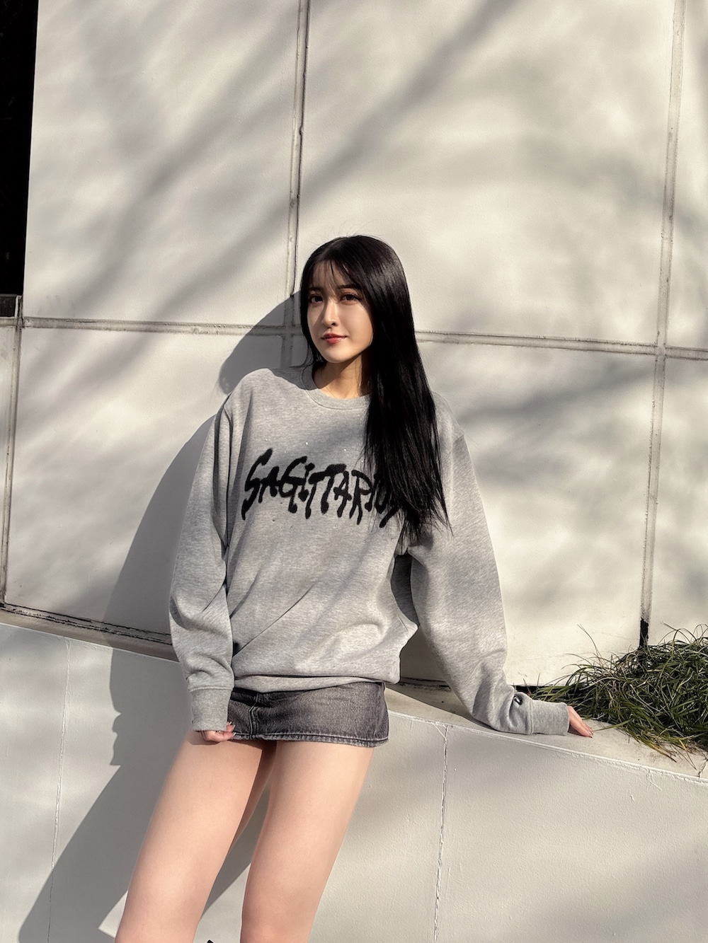 グレー系のスウェット、ブラック系のデニムスカート、ブラック系のブーツを着用したレディースの冬コーディネートの2枚目の写真