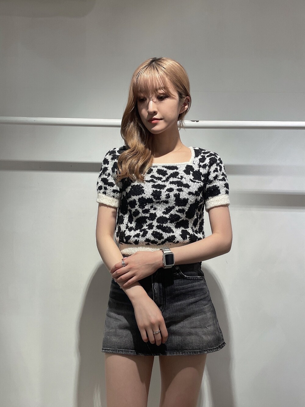 ホワイト系のニット/セーター、ブラック系のデニムスカート、ブラック系のブーツを着用したレディースの夏コーディネートの3枚目の写真