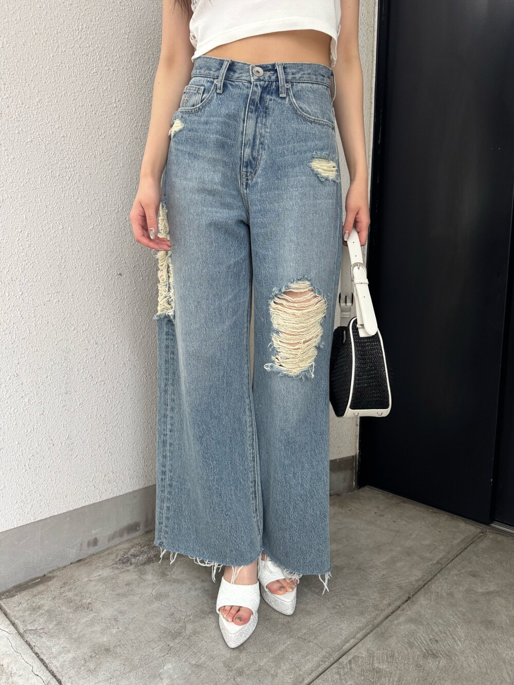 ホワイト系のタンクトップ、ブルー系のデニムパンツ、ホワイト系のパンプスを着用したレディースの夏コーディネートの4枚目の写真