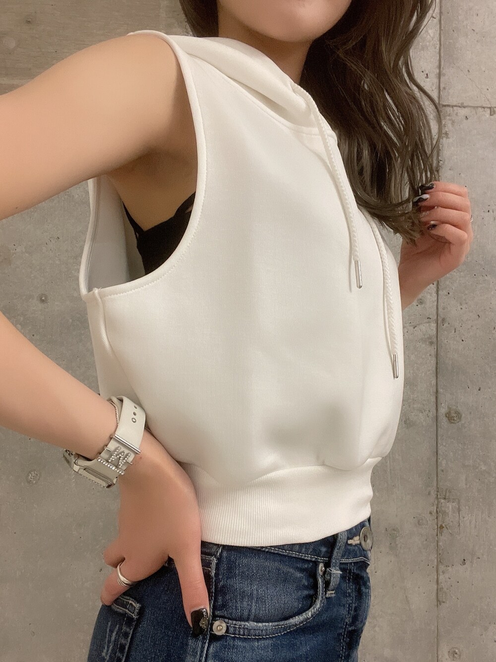 ホワイト系のパーカー、ブラック系のサンダル、ブルー系のデニムパンツを着用したレディースの夏コーディネートの5枚目の写真