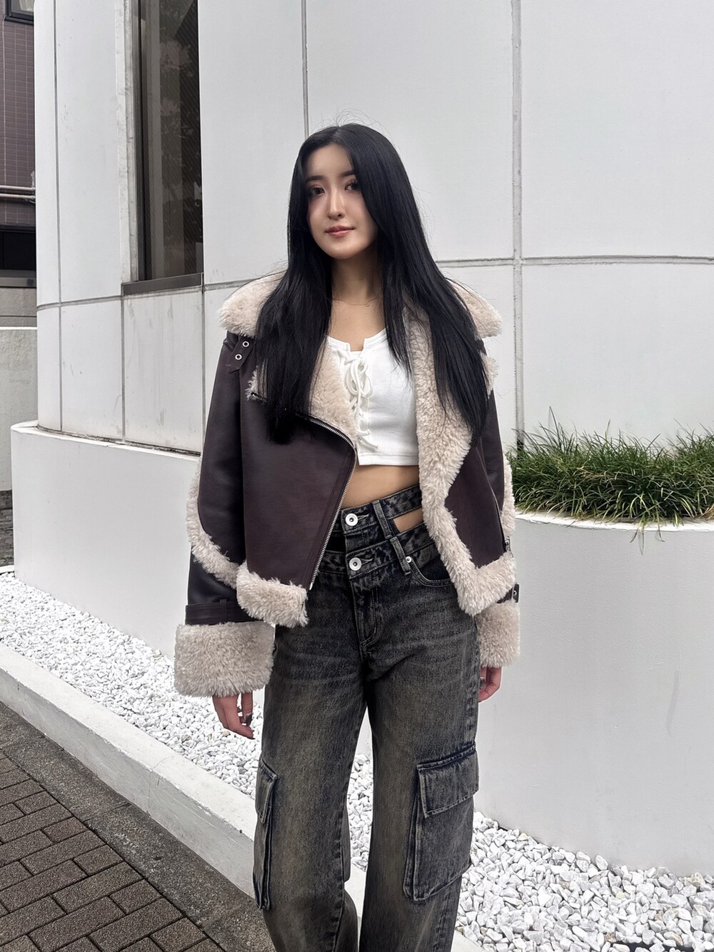 ブラウン系のムートンコート、ホワイト系のTシャツ/カットソー、ブルー系のデニムパンツを着用したレディースの秋コーディネートの2枚目の写真