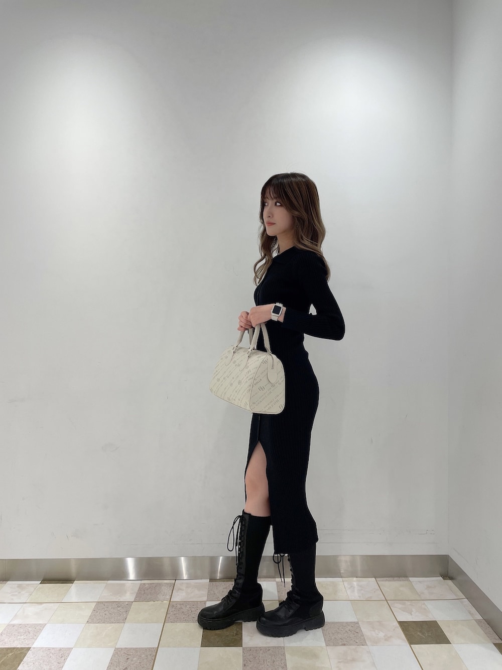 ブラック系のワンピース、ブラック系のブーツ、ホワイト系のボストンバッグを着用したレディースの秋コーディネートの2枚目の写真