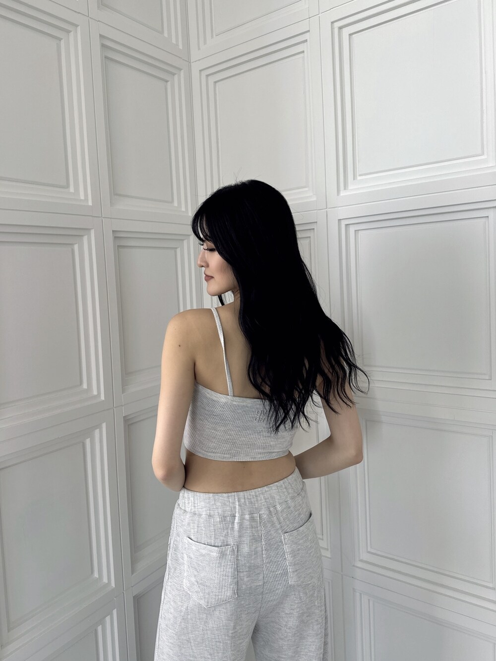 グレー系のキャミソール、グレー系のスウェットパンツ、ブラック系のパンプスを着用したレディースの夏コーディネートの4枚目の写真