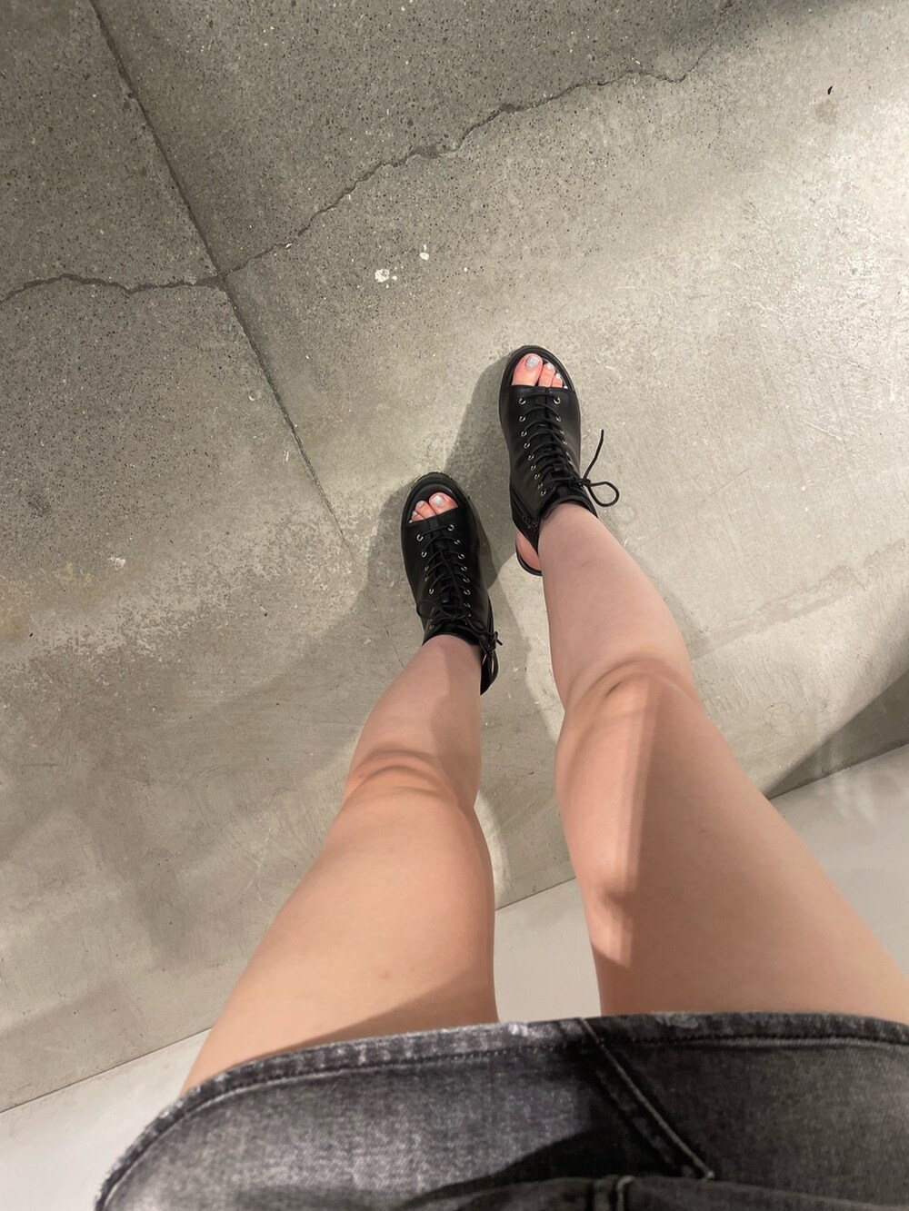 ホワイト系のニット/セーター、ブラック系のデニムスカート、ブラック系のブーツを着用したレディースの夏コーディネートの6枚目の写真