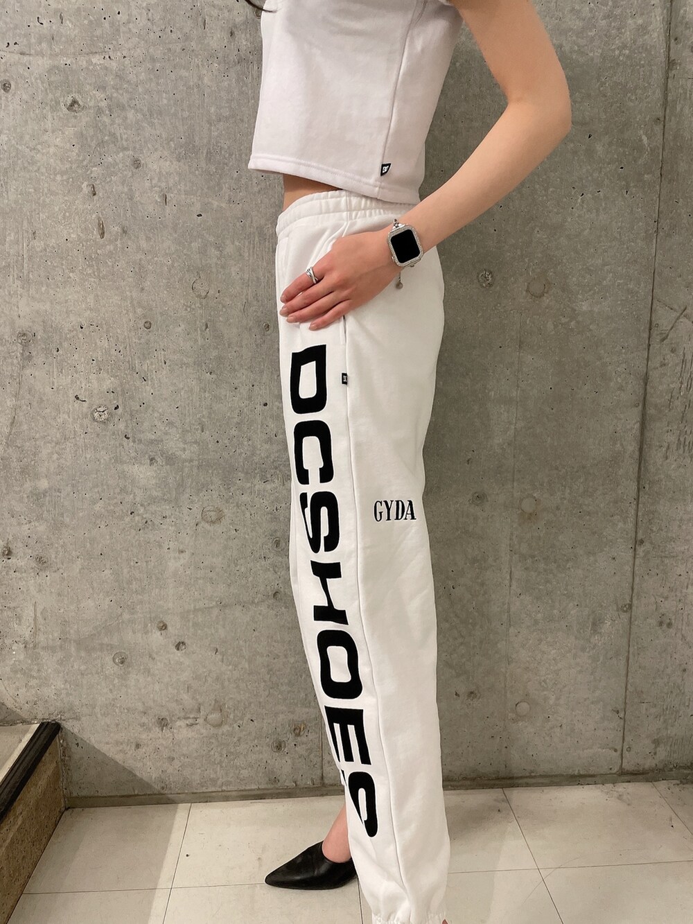 ホワイト系のTシャツ/カットソー、ホワイト系のスウェットパンツ、ブラック系のパンプスを着用したレディースの春コーディネートの5枚目の写真