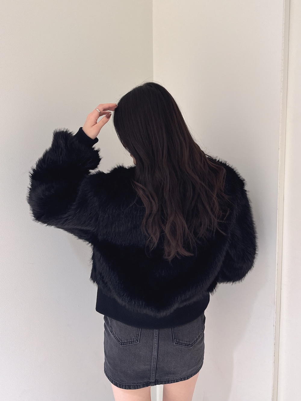 ブラック系のその他アウター、ブラック系のニット/セーター、ブラック系のデニムスカートを着用したレディースの秋コーディネートの4枚目の写真