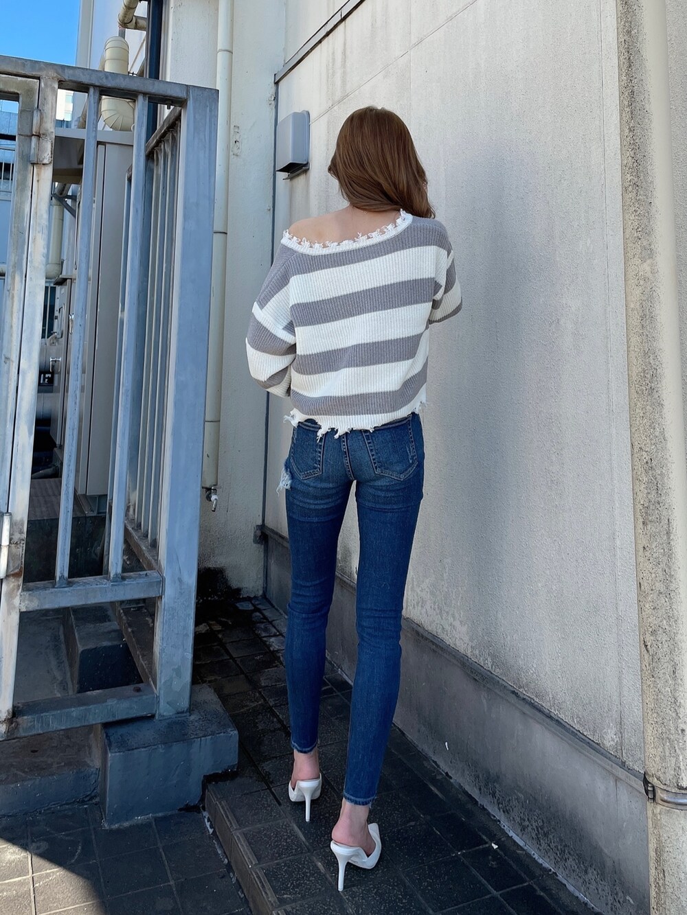 ブルー系のデニムパンツ、グレー系のニット/セーター、ホワイト系のパンプスを着用したレディースの冬コーディネートの2枚目の写真