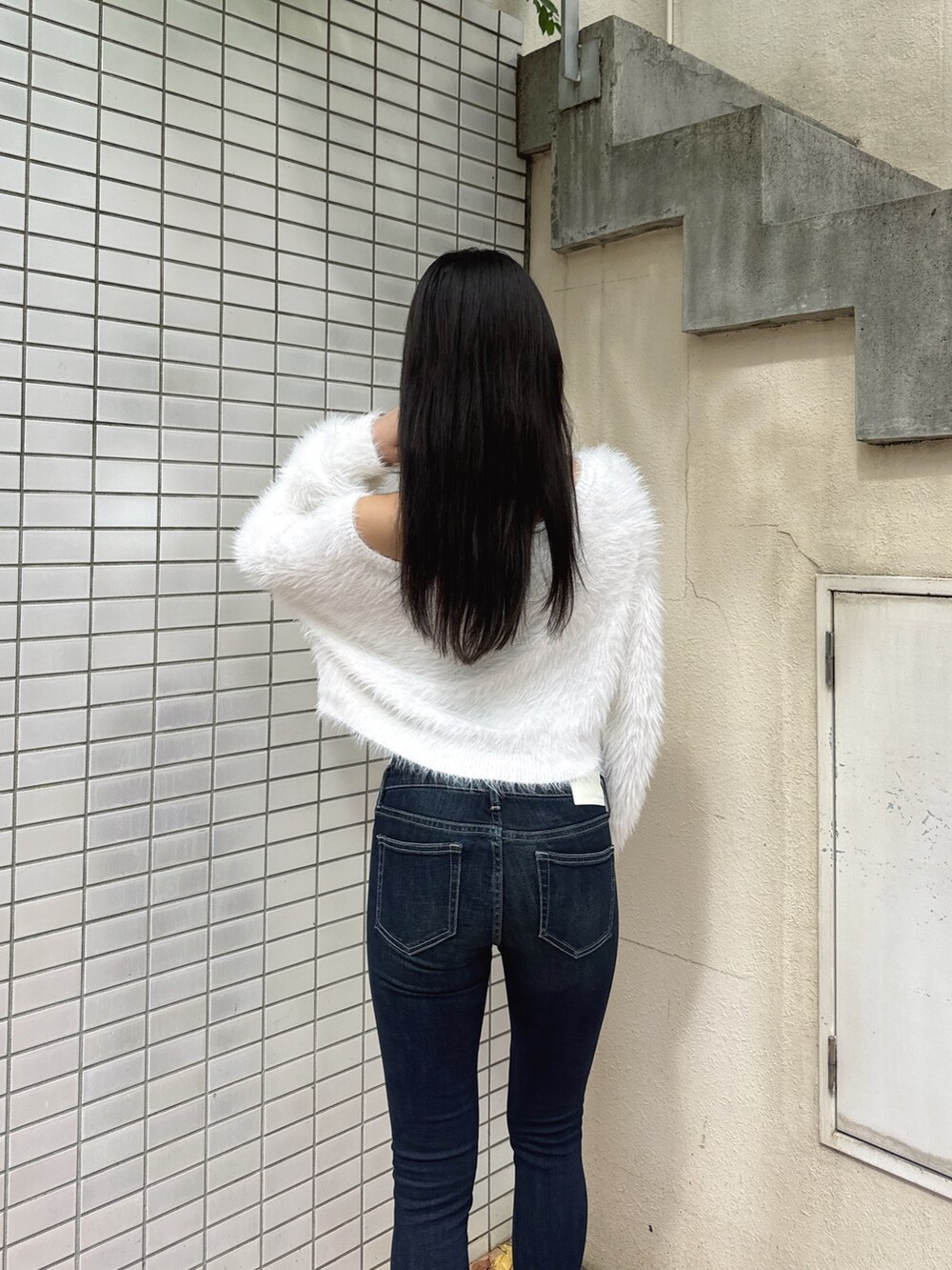 ホワイト系のニット/セーター、ブルー系のデニムパンツ、ブラック系のパンプスを着用したレディースの冬コーディネートの4枚目の写真