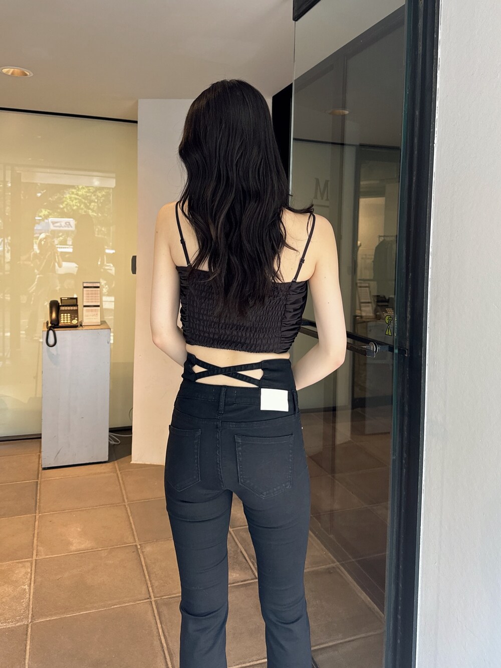 ブラック系のキャミソール、ブラック系のデニムパンツ、ブラック系のサンダルを着用したレディースの夏コーディネートの4枚目の写真