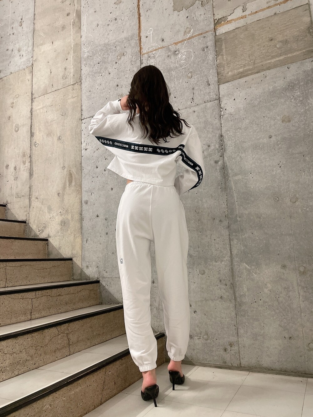 ホワイト系のTシャツ/カットソー、ホワイト系のスウェットパンツ、ブラック系のパンプスを着用したレディースの春コーディネートの3枚目の写真