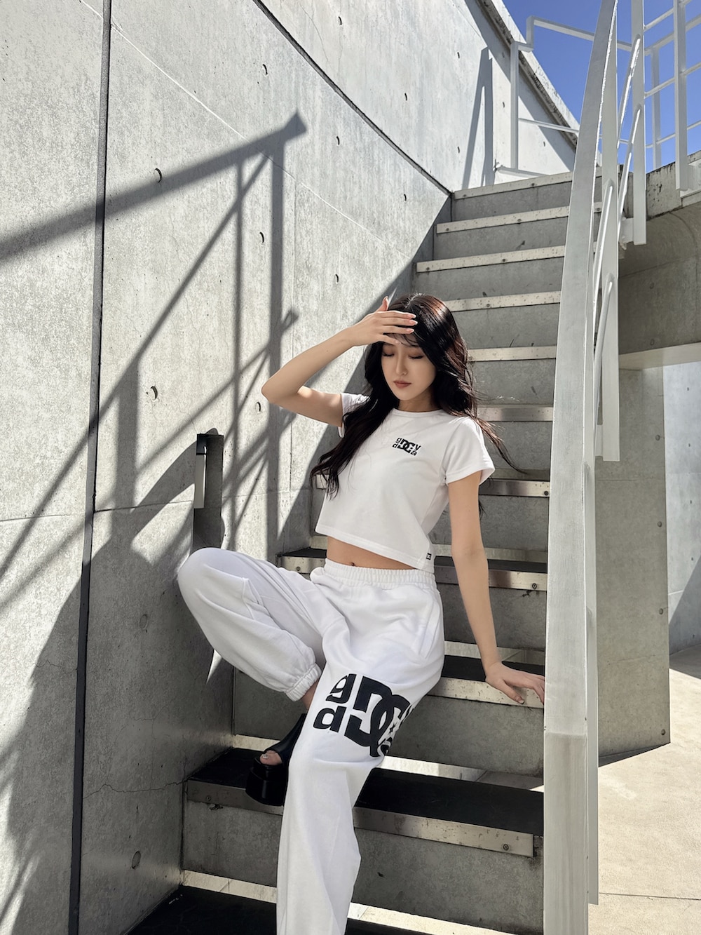 ホワイト系のTシャツ/カットソー、ホワイト系のスウェットパンツ、ブラック系のサンダルを着用したレディースの春コーディネートの2枚目の写真