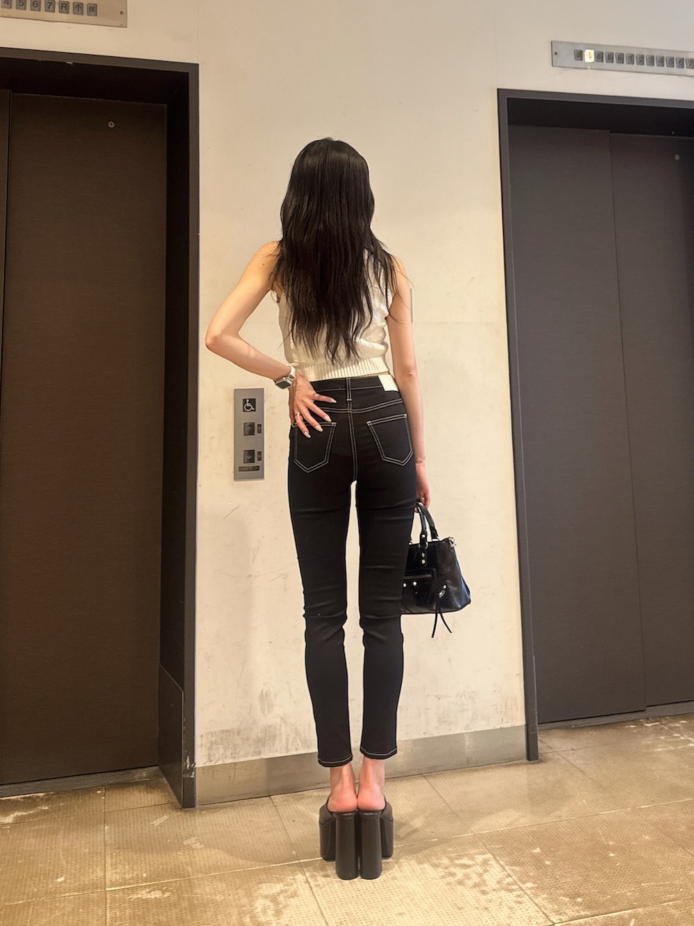 ホワイト系のニット/セーター、ブラック系のデニムパンツ、その他のサンダルを着用したレディースの夏コーディネートの5枚目の写真