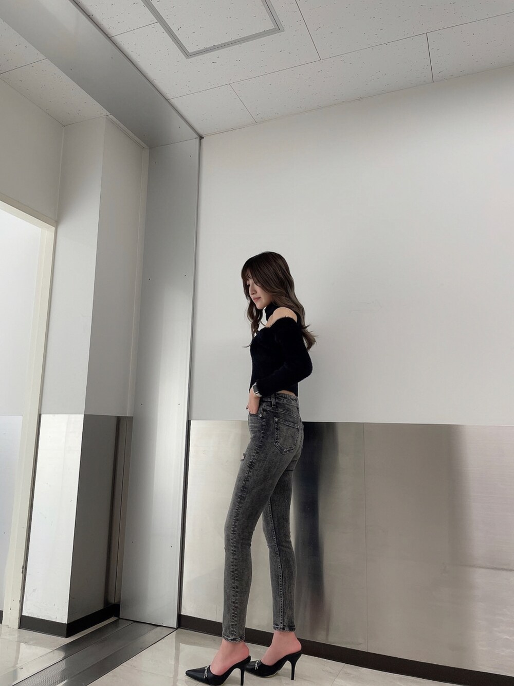 ブラック系のデニムパンツ、ブラック系のニット/セーター、ブラック系のパンプスを着用したレディースの秋コーディネートの2枚目の写真