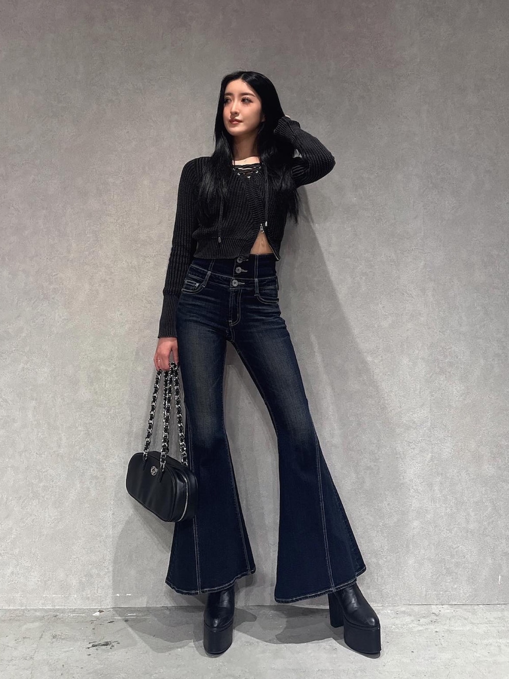 ブラック系のニット/セーター、ブルー系のデニムパンツ、ブラック系のブーツを着用したレディースの秋コーディネートの3枚目の写真