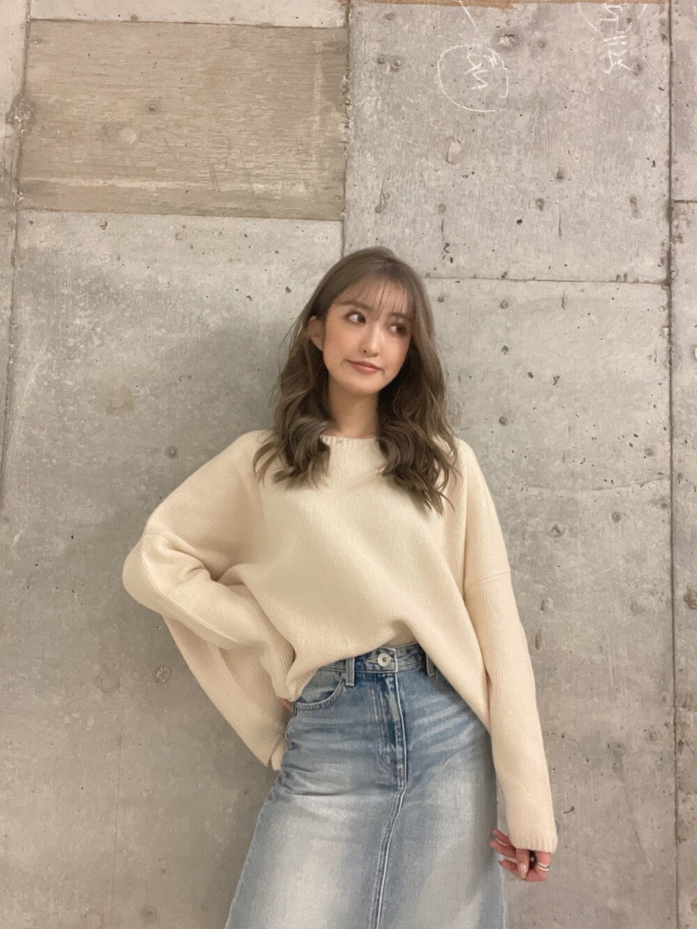 ホワイト系のニット/セーター、ブルー系のデニムスカート、ホワイト系のパンプスを着用したレディースの冬コーディネートの3枚目の写真