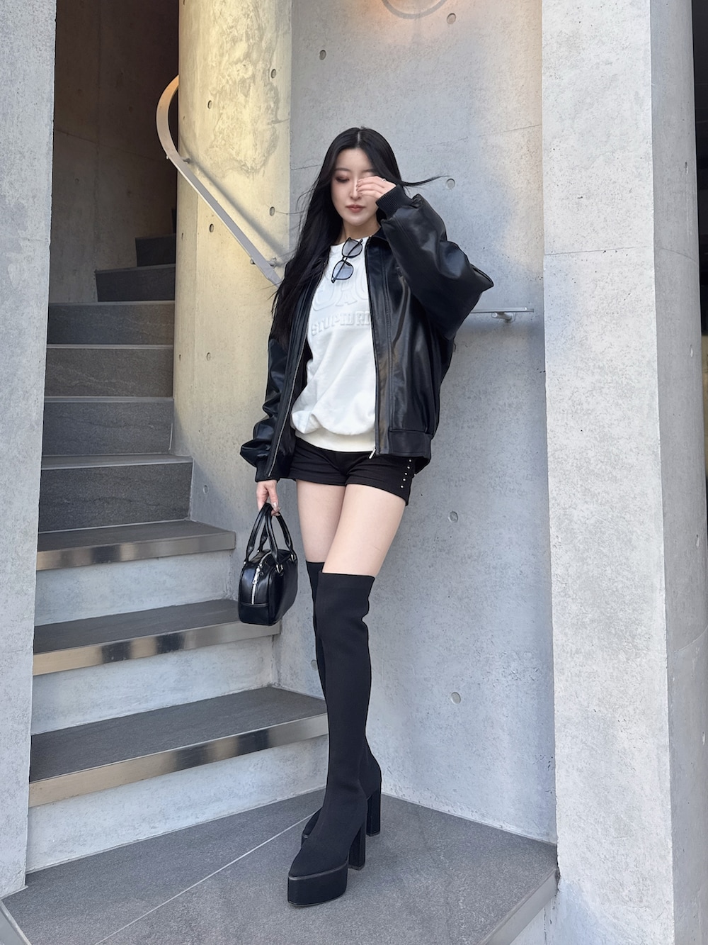 ブラック系のブルゾン、ブラック系のブーツ、ホワイト系のスウェットを着用したレディースの冬コーディネートの2枚目の写真