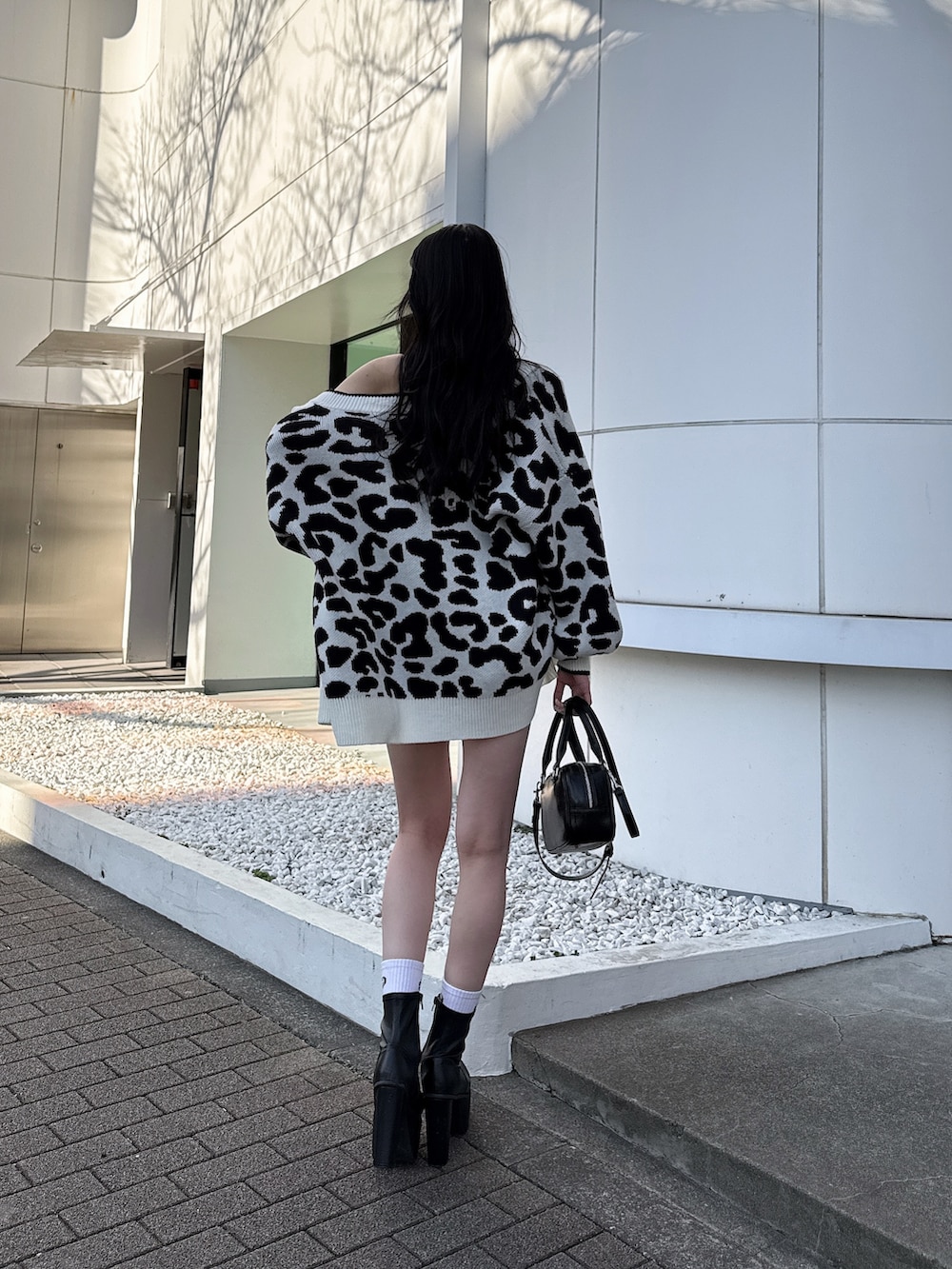 ホワイト系のカーディガン/ボレロ、ブラック系のキャミソール、ブラック系のデニムパンツを着用したレディースの春コーディネートの2枚目の写真