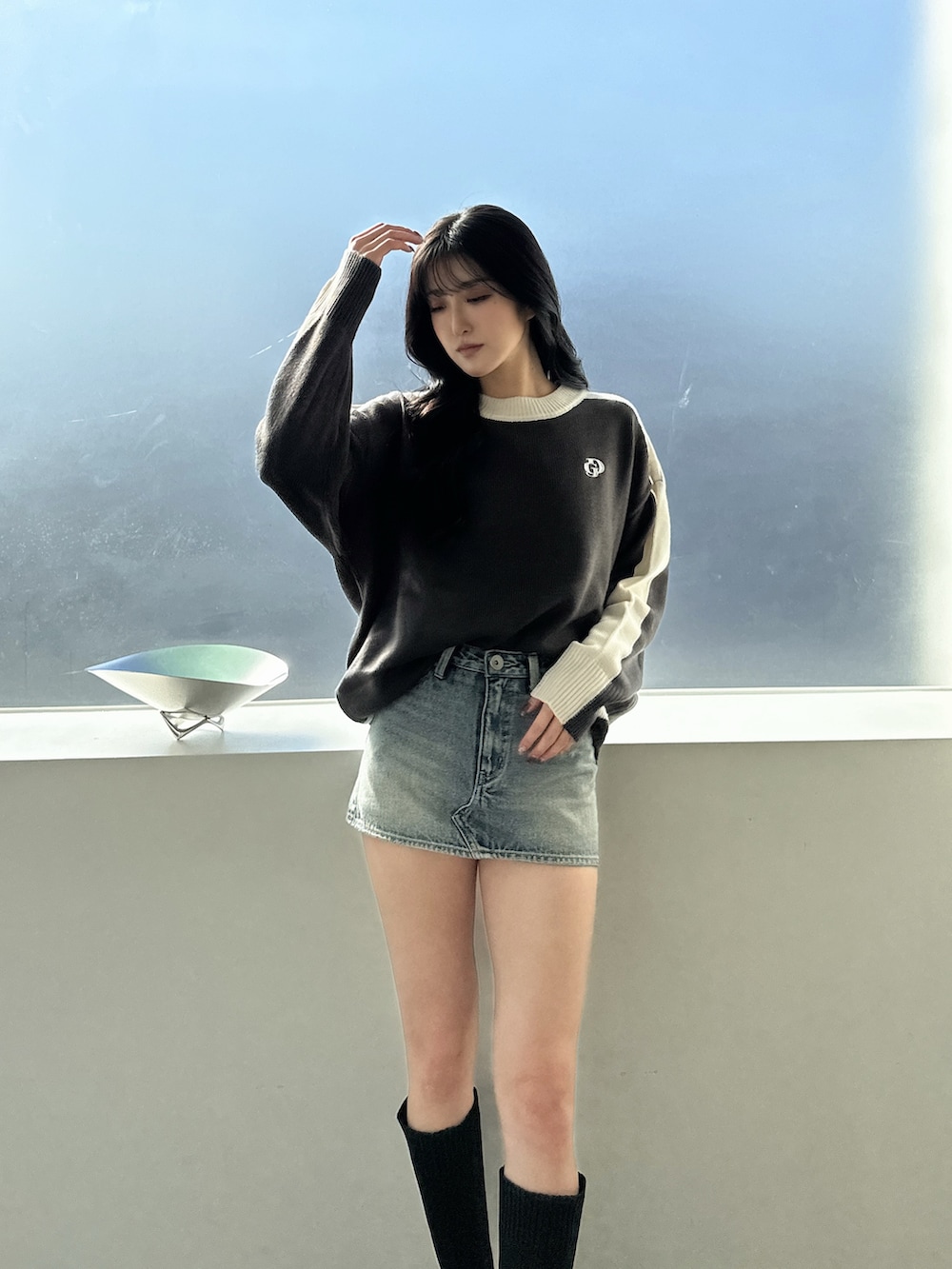 グレー系のニット/セーター、ブルー系のデニムスカート、ブラック系のブーツを着用したレディースの冬コーディネートの3枚目の写真