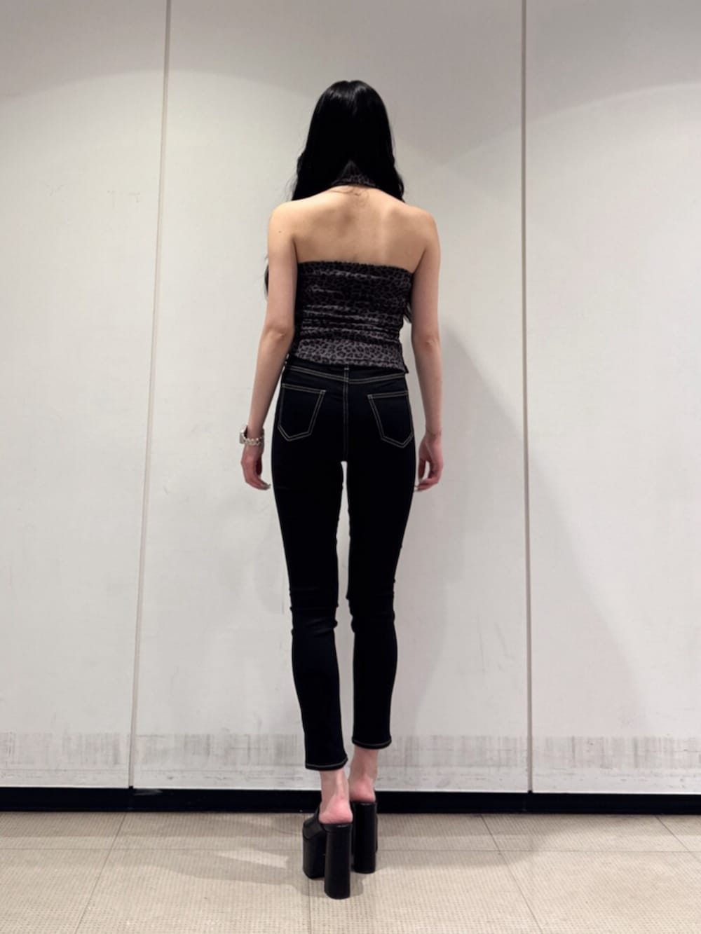 ブラック系のデニムパンツ、ブラック系のサンダル、その他のチューブトップを着用したレディースの夏コーディネートの3枚目の写真