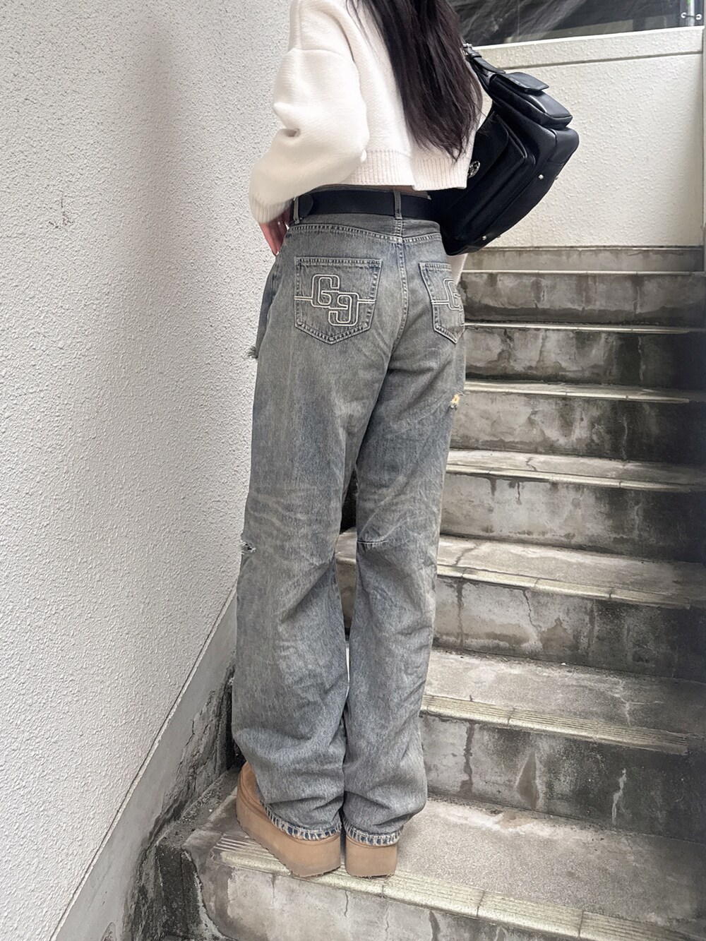 ホワイト系のニット/セーター、ブルー系のデニムパンツ、ブラック系のハンドバッグを着用したレディースの秋コーディネートの5枚目の写真