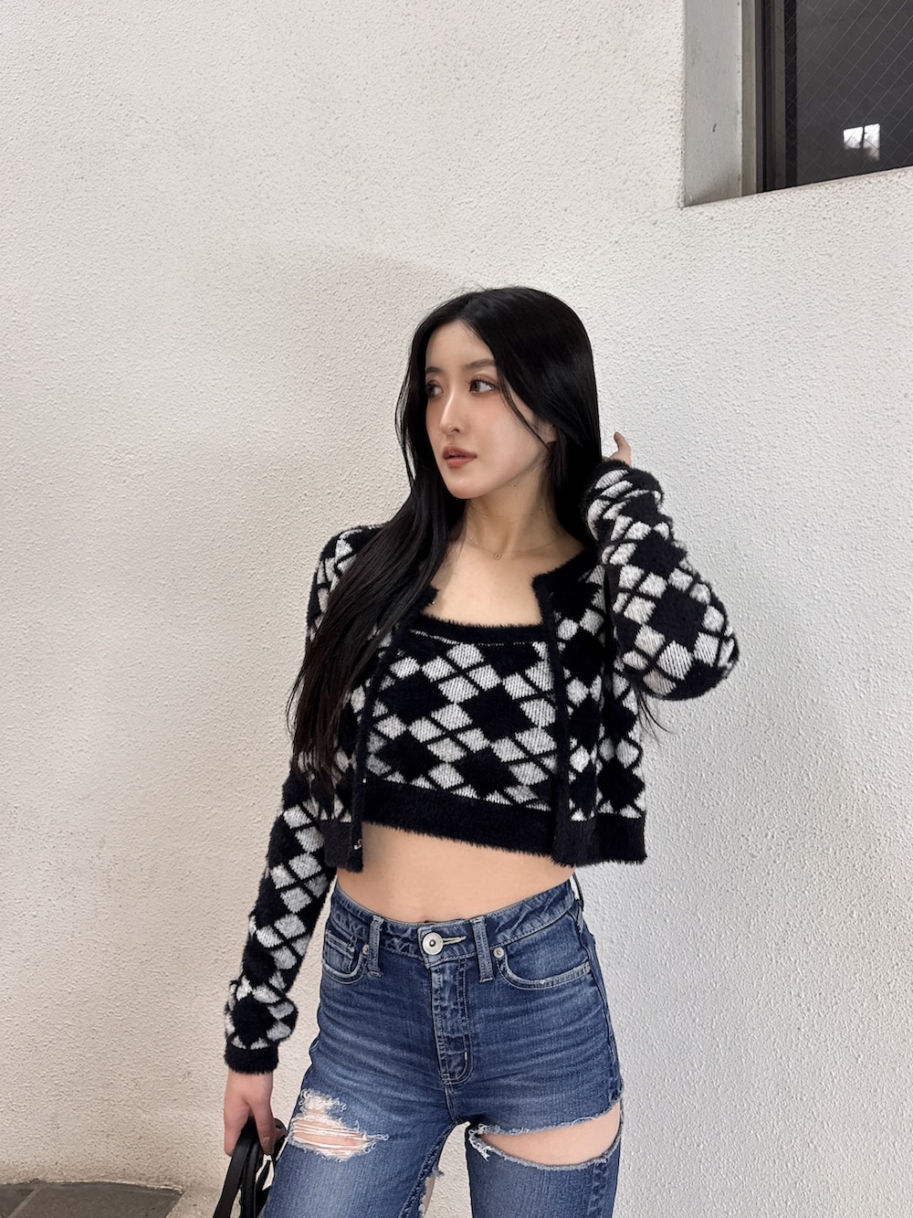 ブラック系のキャミソール、ブラック系のカーディガン/ボレロ、ブルー系のデニムパンツを着用したレディースの冬コーディネートの4枚目の写真