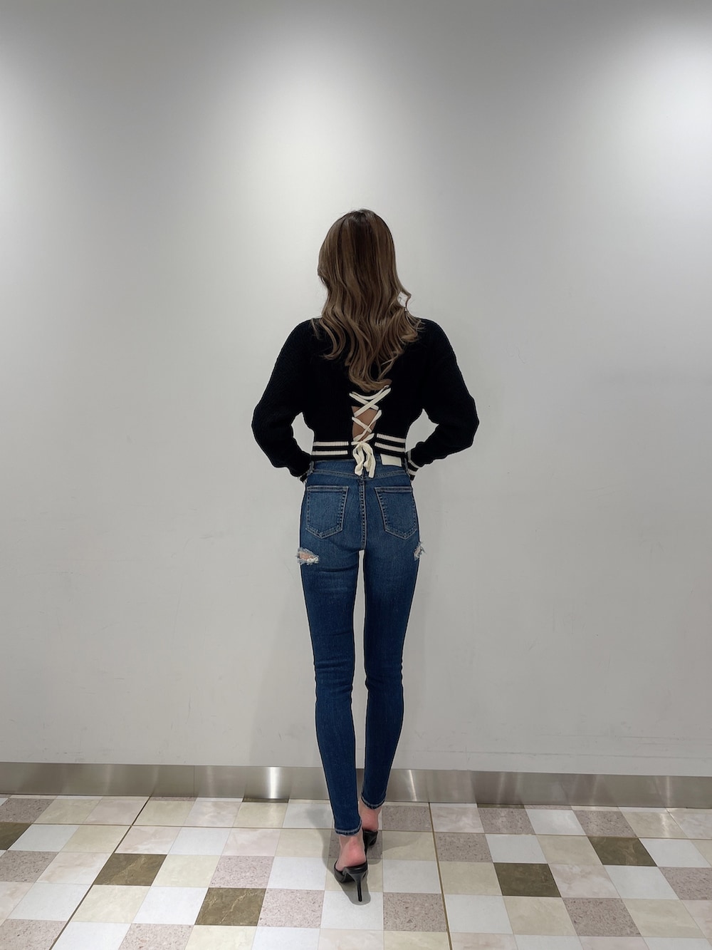 ブラック系のニット/セーター、ブルー系のデニムパンツ、ブラック系のパンプスを着用したレディースの秋コーディネートの2枚目の写真