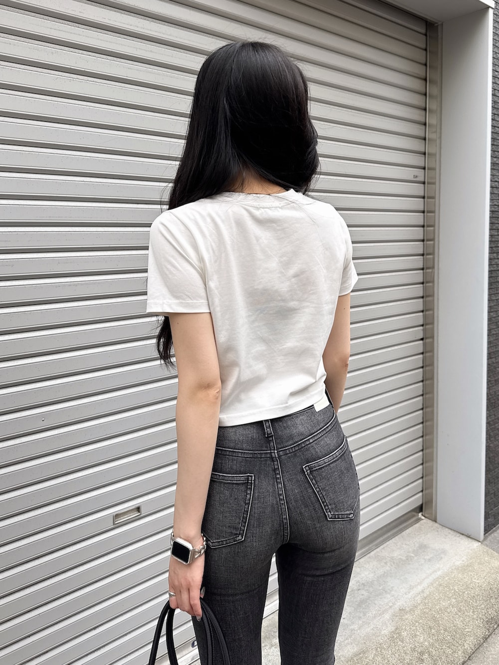 ホワイト系のTシャツ/カットソー、ブラック系のデニムパンツ、ブラック系のボストンバッグを着用したレディースの夏コーディネートの6枚目の写真