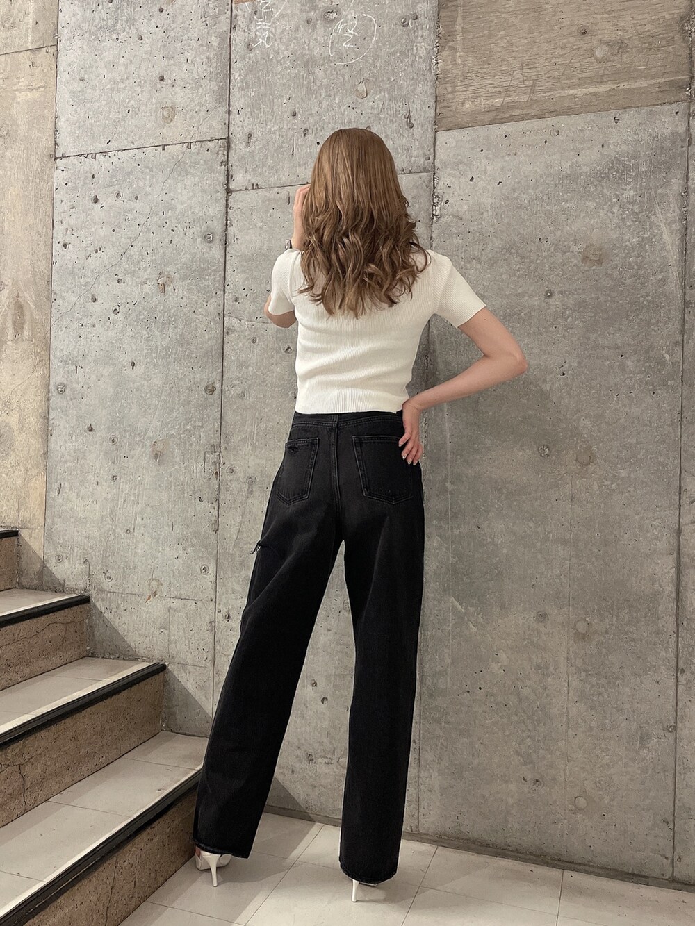 ブラック系のデニムパンツ、ホワイト系のパンプス、ホワイト系のニット/セーターを着用したレディースの夏コーディネートの2枚目の写真