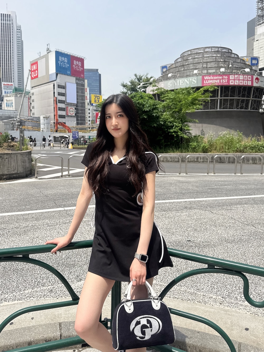 ブラック系のワンピース、ブラック系のハンドバッグ、ブラック系のスニーカーを着用したレディースの春コーディネートの2枚目の写真