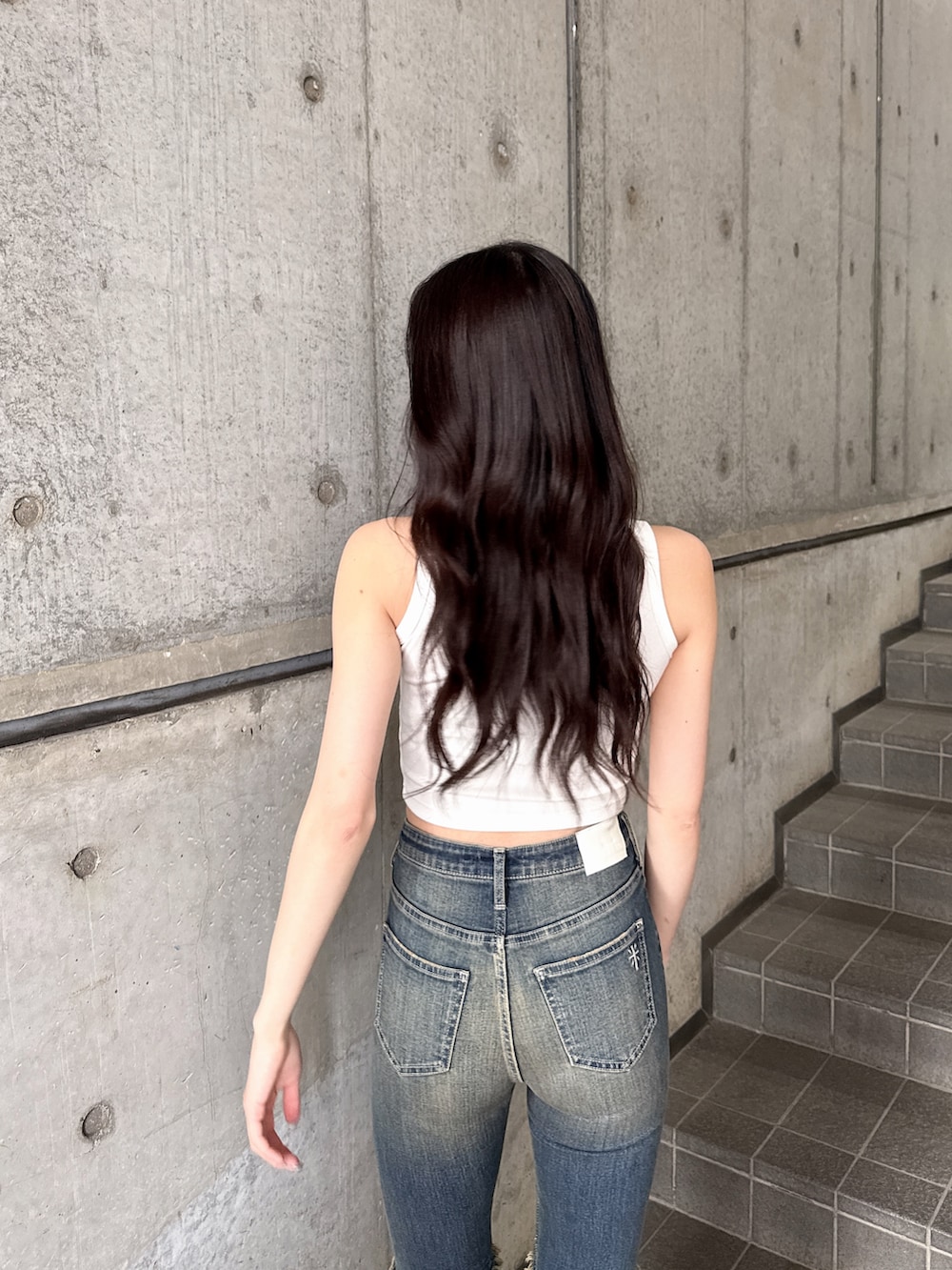 ホワイト系のタンクトップ、ブルー系のデニムパンツ、ホワイト系のサンダルを着用したレディースの春コーディネートの4枚目の写真