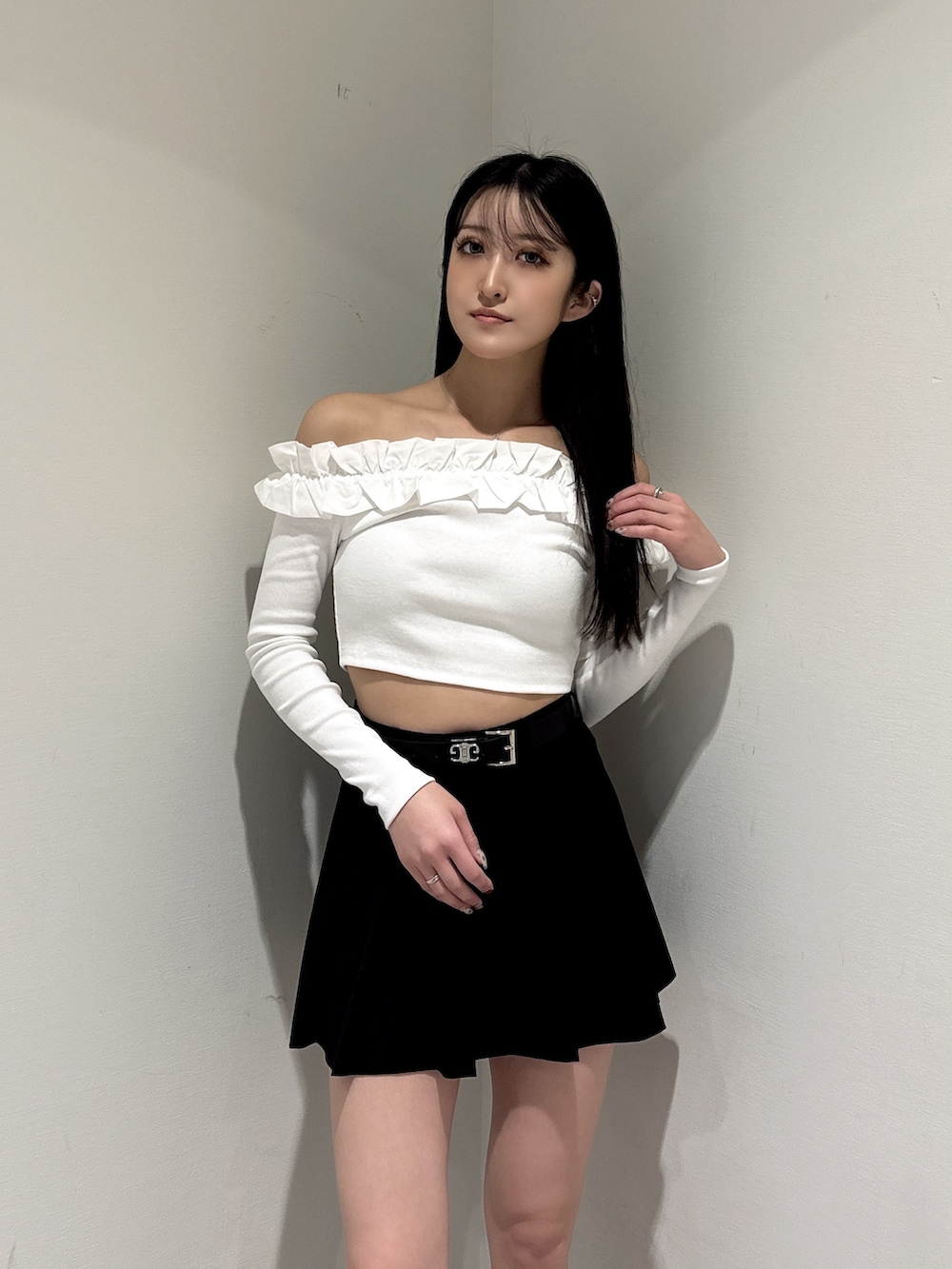 ホワイト系のTシャツ/カットソー、ブラック系のスカート、ブラック系のブーツを着用したレディースの冬コーディネートの3枚目の写真