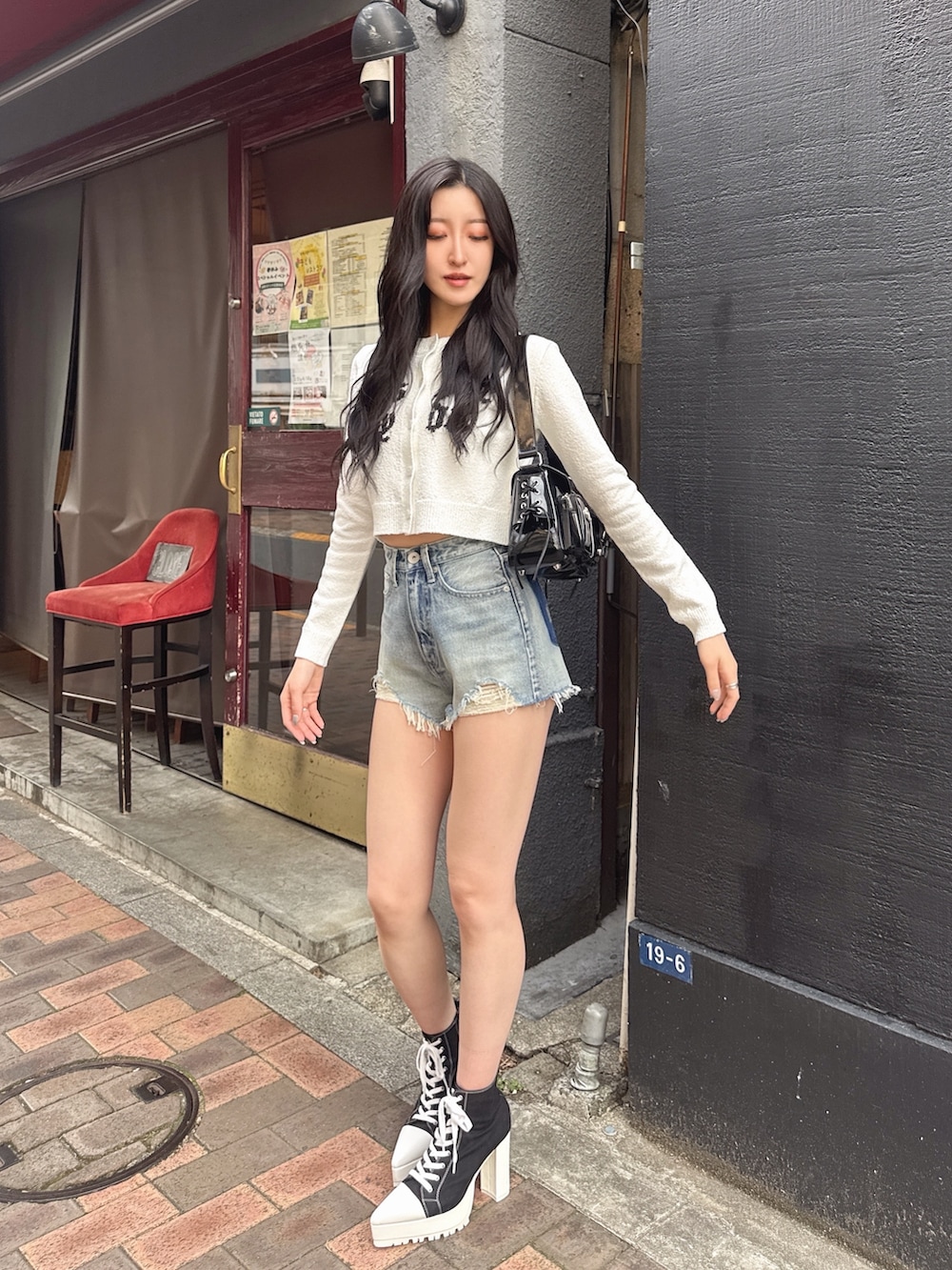 ブルー系のデニムパンツ、ブラック系のブーツ、ホワイト系のカーディガン/ボレロを着用したレディースの春コーディネートの3枚目の写真