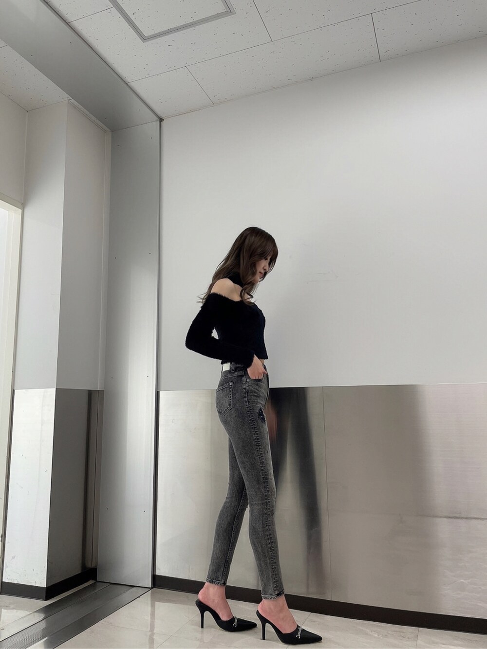 ブラック系のデニムパンツ、ブラック系のニット/セーター、ブラック系のパンプスを着用したレディースの秋コーディネートの4枚目の写真