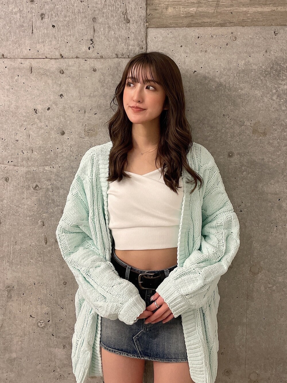 グリーン系のカーディガン/ボレロ、ホワイト系のTシャツ/カットソー、ブルー系のデニムスカートを着用したレディースの冬コーディネートの2枚目の写真