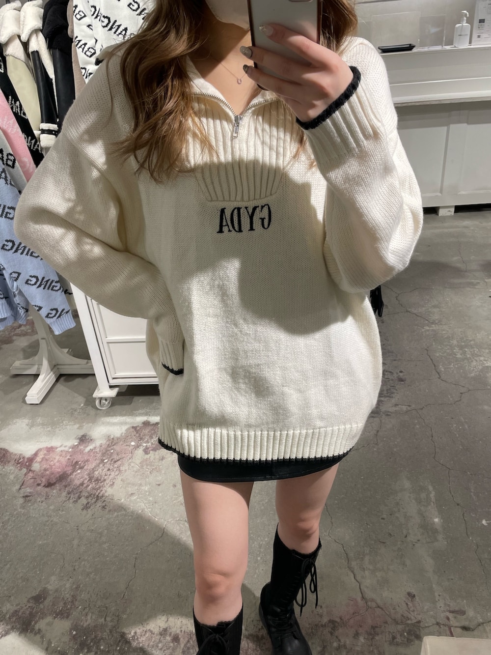 ホワイト系のニット/セーター、ブラック系のスカート、ブラック系のブーツを着用したレディースの冬コーディネートの2枚目の写真