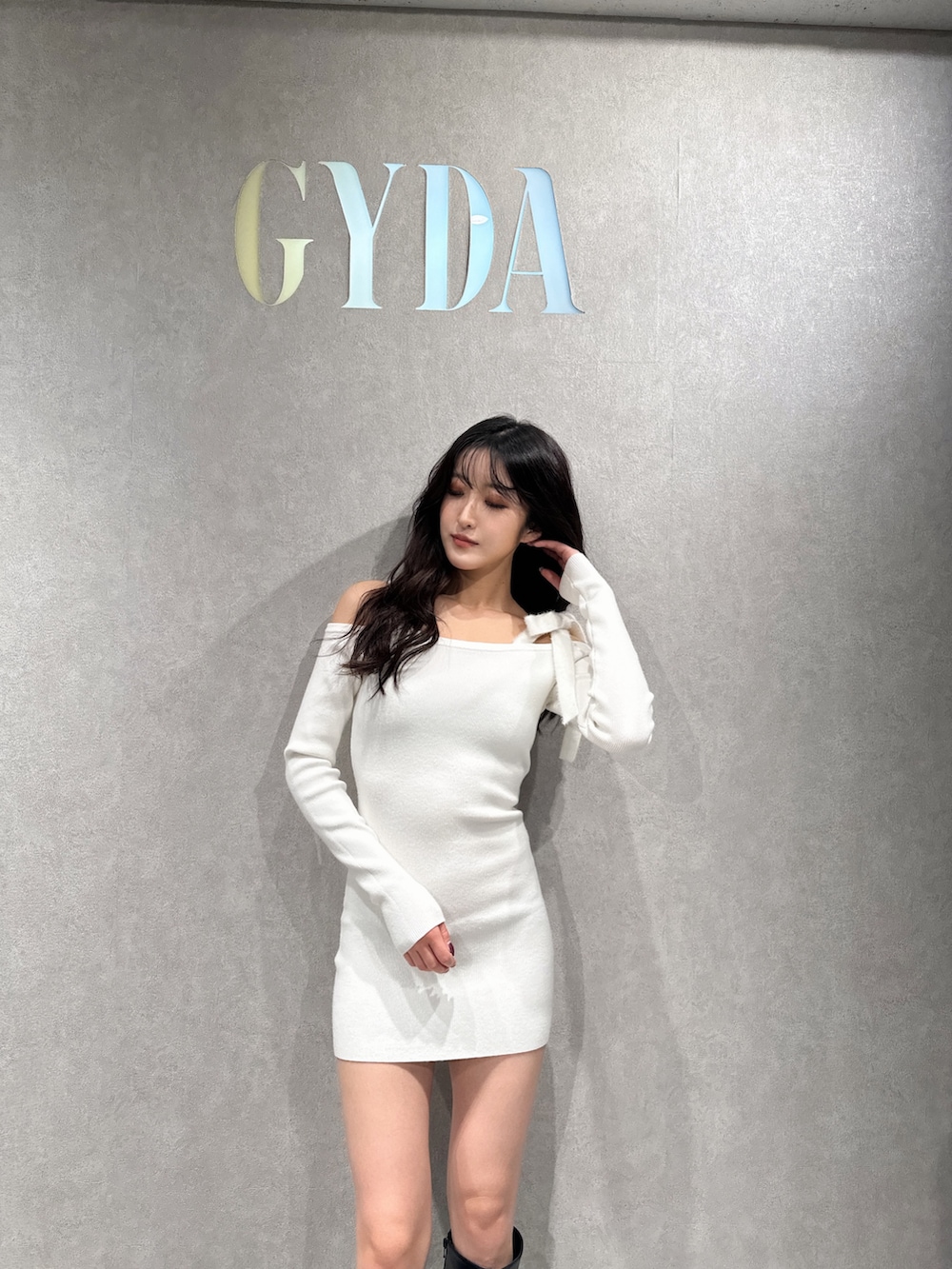 ホワイト系のワンピース、ブラック系のブーツを着用したレディースの冬コーディネートの2枚目の写真