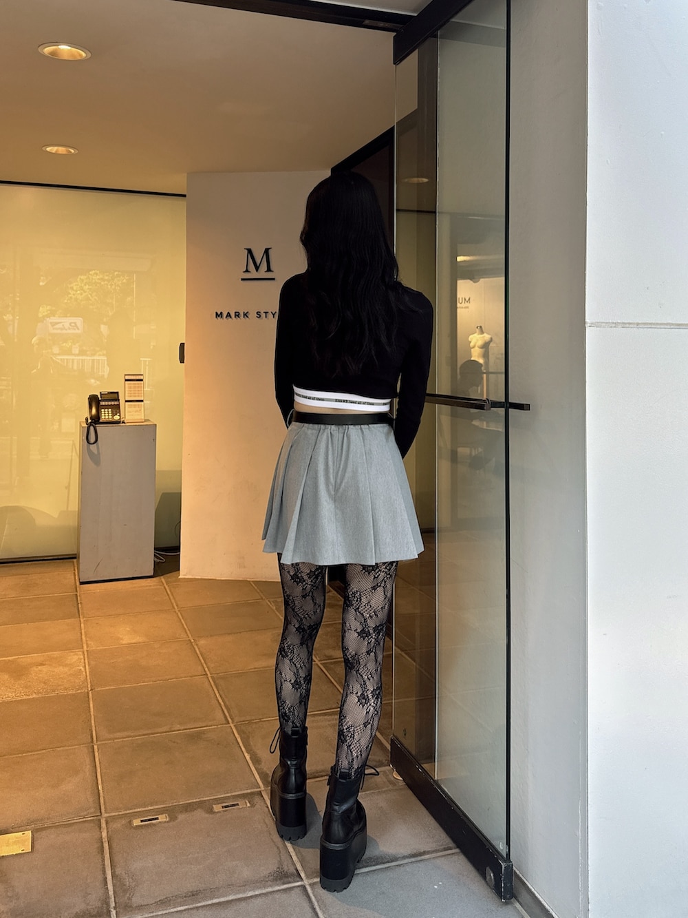 ブラック系のTシャツ/カットソー、グレー系のスカート、ブラック系のブーツを着用したレディースの夏コーディネートの2枚目の写真