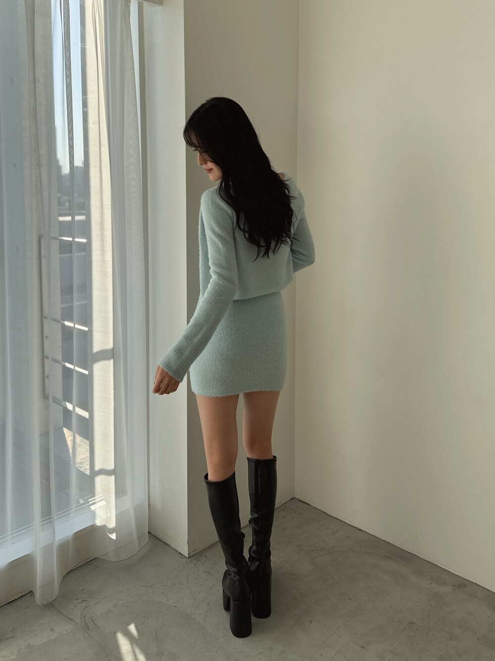 ブルー系のカーディガン/ボレロ、ブルー系のワンピース、ブラック系のブーツを着用したレディースの冬コーディネートの3枚目の写真